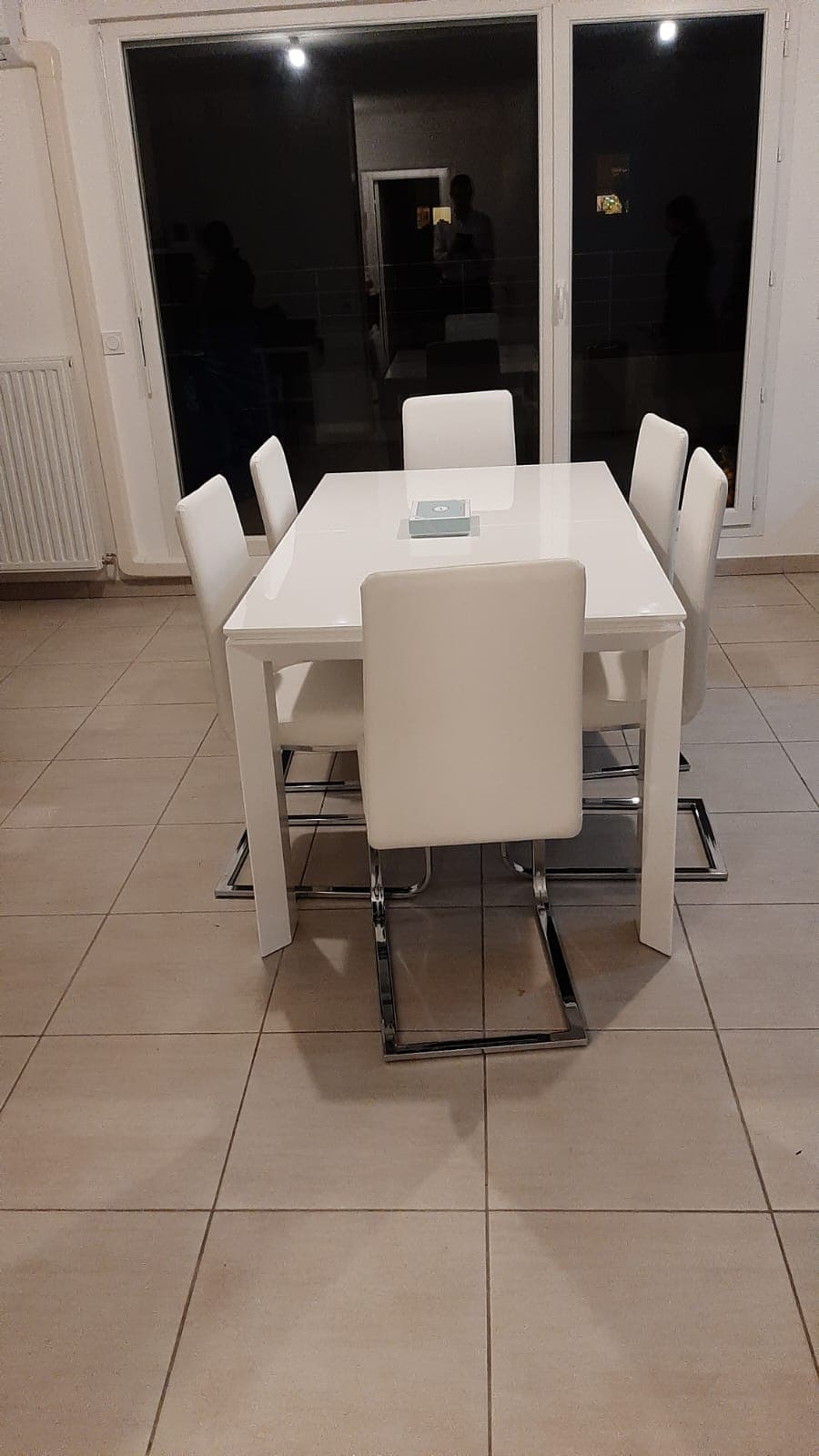 Table de repas rectangulaire laquée blanc brillant à pieds carrés d’angle, plateau à allonge, entourée de chaises blanches à piètement chromé