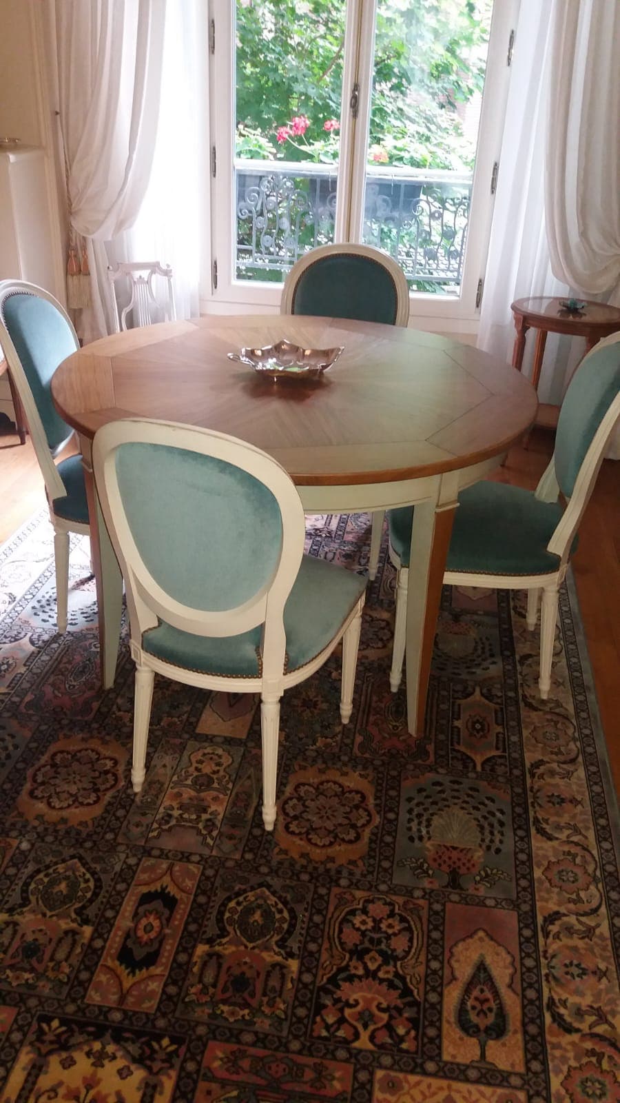 Table ronde à plateau de merisier composé en rayonnant, ceinture et pieds fuselés cannelés laqués crème, entourée de six chaises médaillon en velours céladon