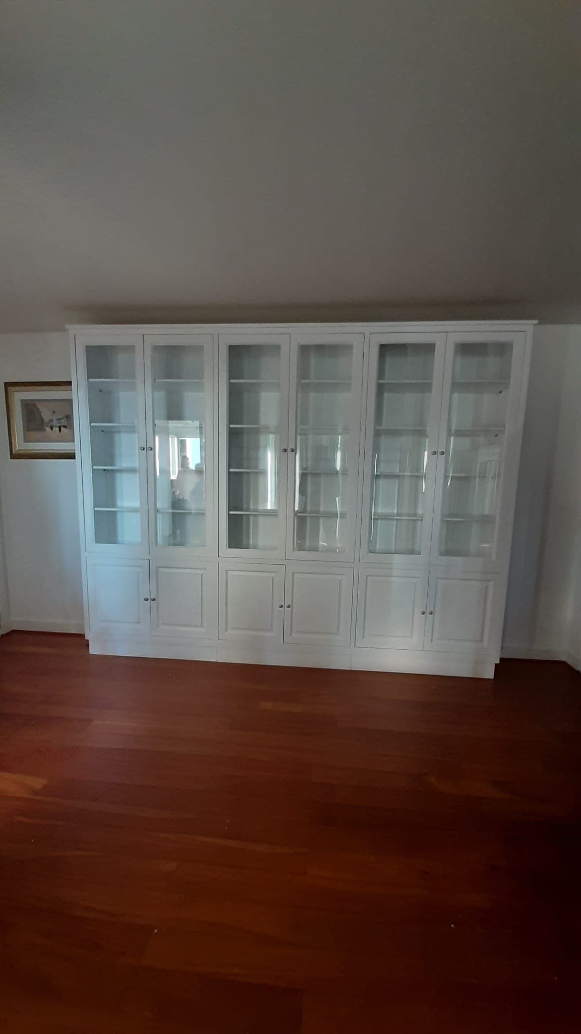 Bibliothèque-vitrine de 3 mètres laquée blanc en trois modules : six portes vitrées toute hauteur sur tablettes réglables et six portes à panneaux moulurés en buffet bas