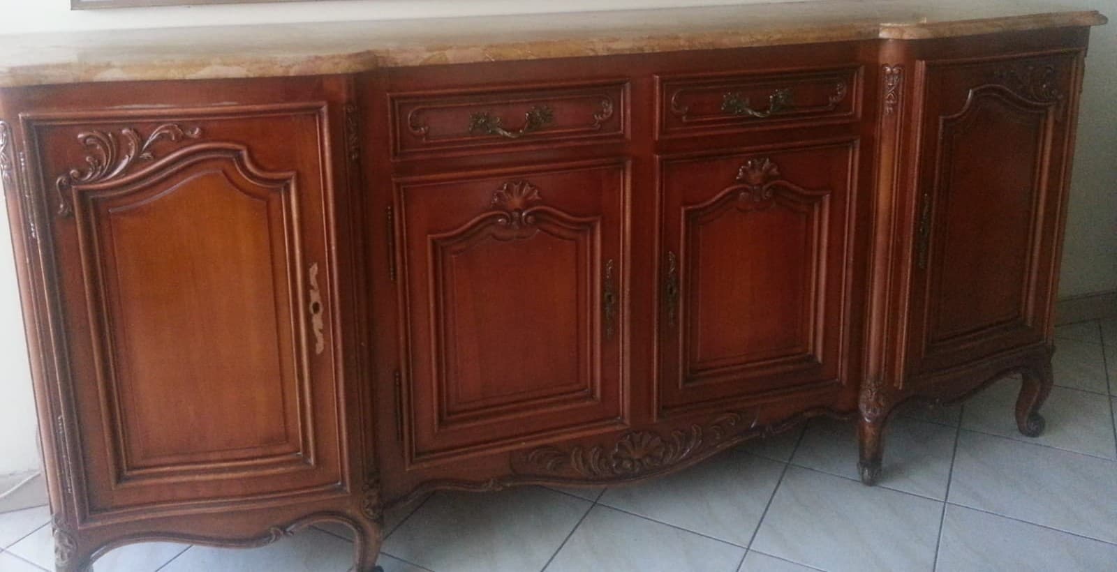 Grande enfilade Louis XV en merisier massif à dessus de marbre ocre veiné : corps central en ressaut, quatre portes à panneaux galbés ornés de coquilles sculptées, deux tiroirs à poignées rocaille et pieds cambrés à sabots