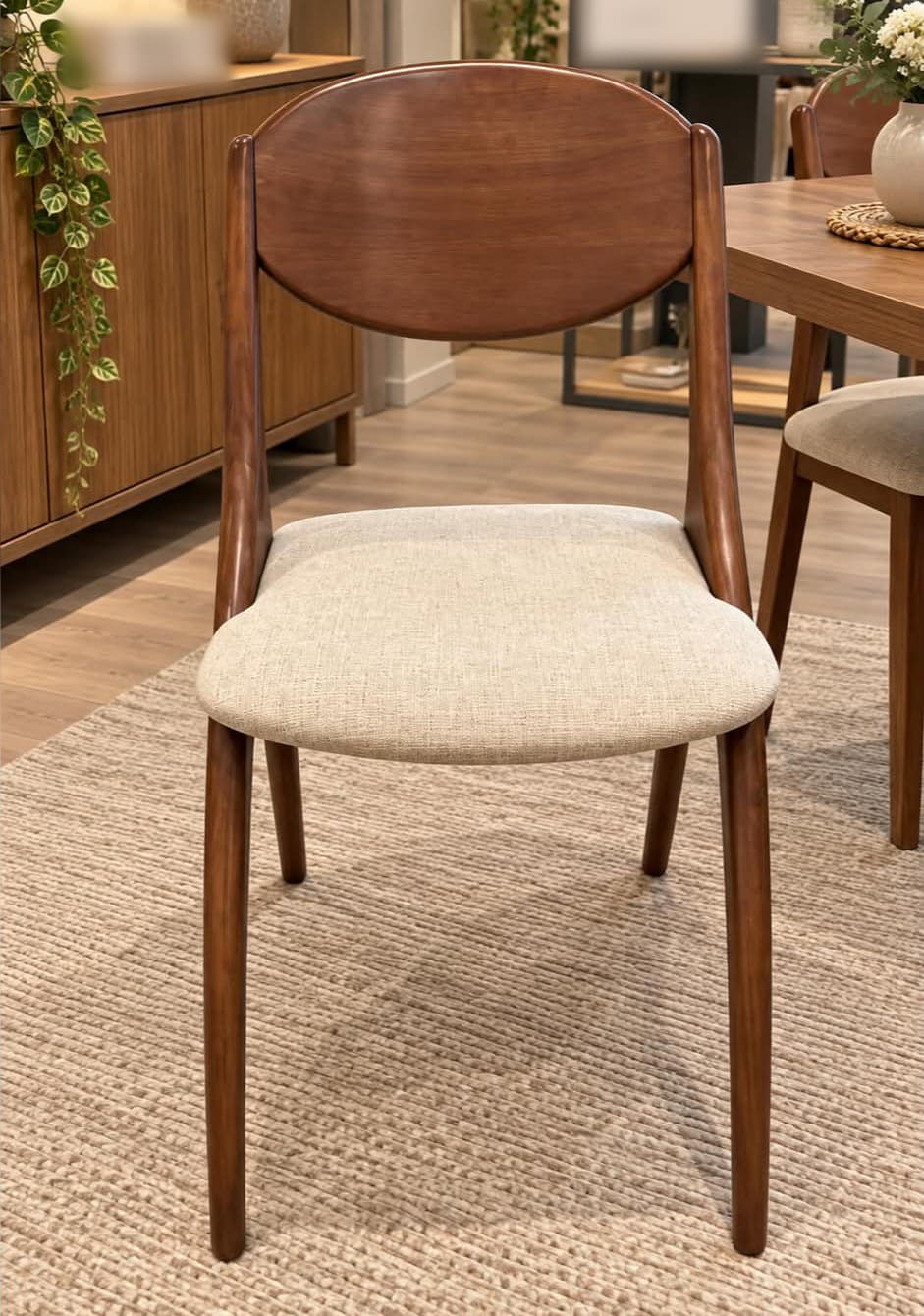 Chaise d’inspiration scandinave en bois massif, dossier ovale plein légèrement cintré, assise galbée garnie de tissu grège, pieds fuselés évasés