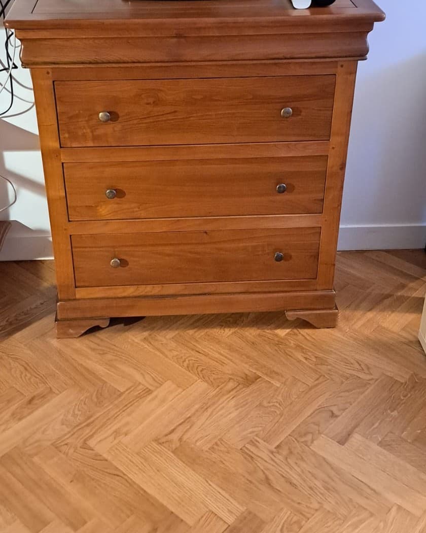 Petite commode Louis-Philippe en merisier massif de 90 cm : trois tiroirs à boutons de laiton, quatrième tiroir dissimulé dans la ceinture en doucine, plateau mouluré et socle à pieds découpés