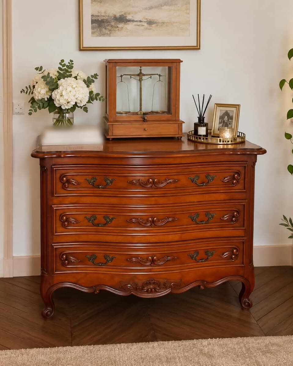 Commode Louis XV en merisier massif à façade galbée en arbalète, trois tiroirs ornés de feuillages sculptés et de poignées en bronze rocaille, tablier chantourné à coquille et pieds cambrés à enroulement
